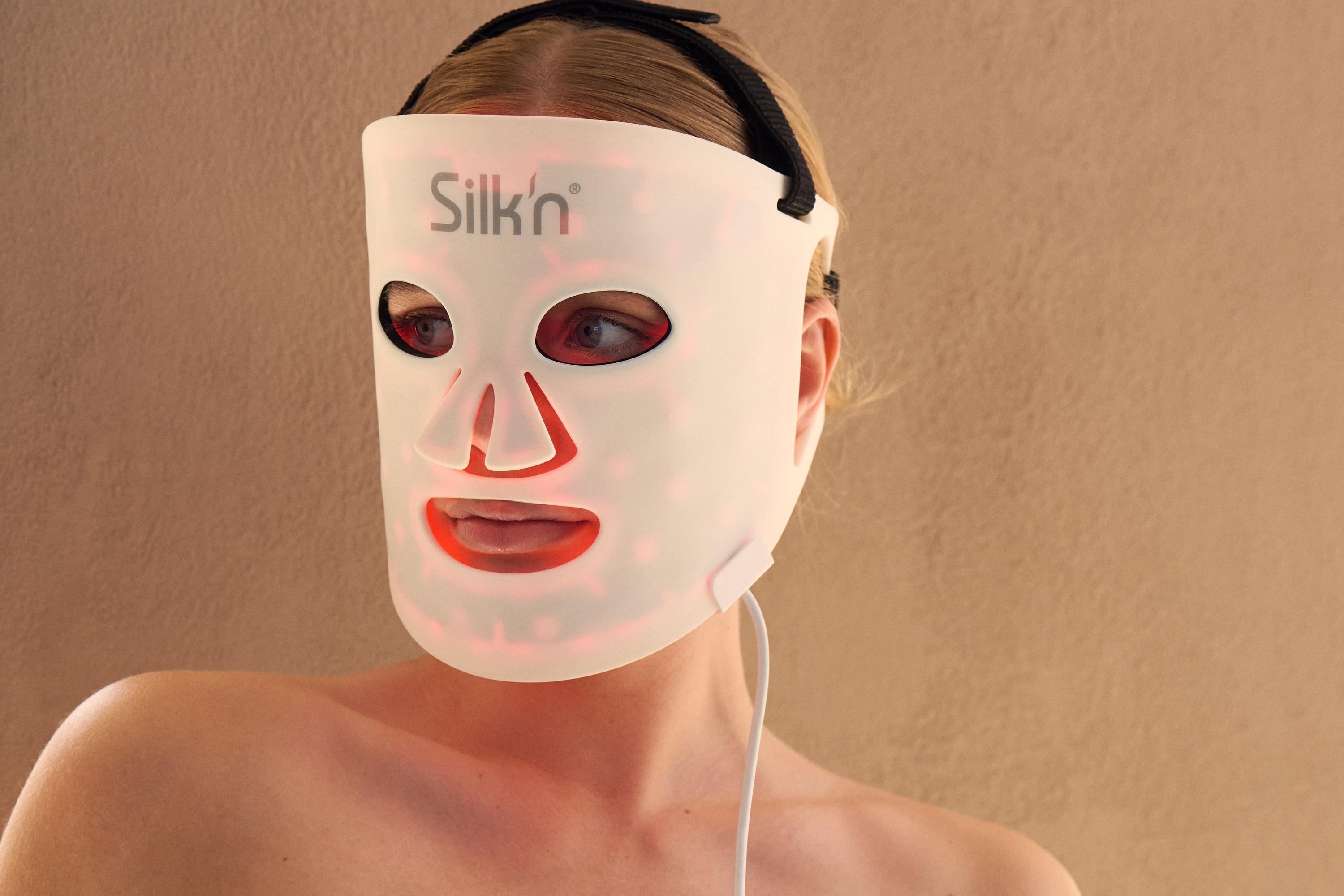Woman using the LED Face Mask 100 of Silk'n with the goal to improve her skin and glow thanks to LED technology