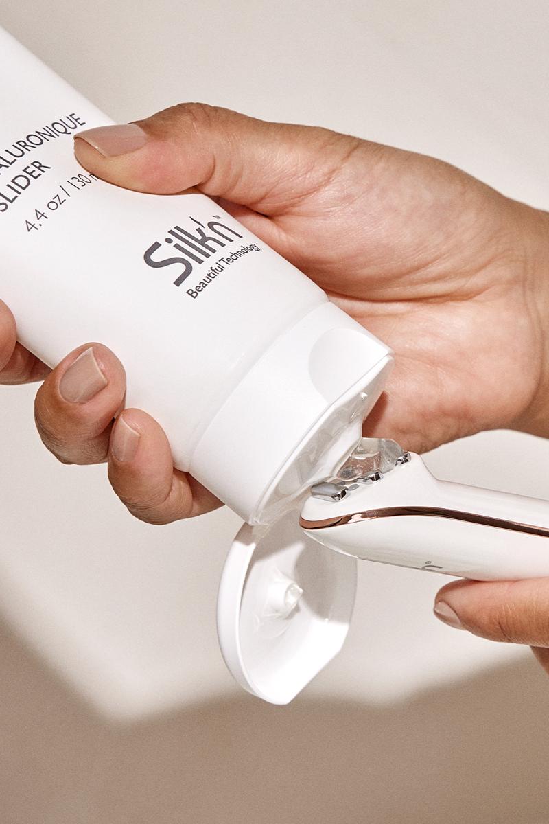 Woman applying hyaluronic gel to the Silk'n Titan Mini Skin Tightening device, anti-aging treatment.