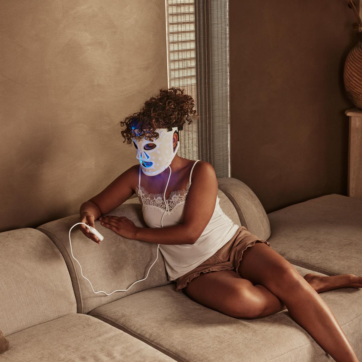 Woman using led light therapy on face with led face mask Silk'n