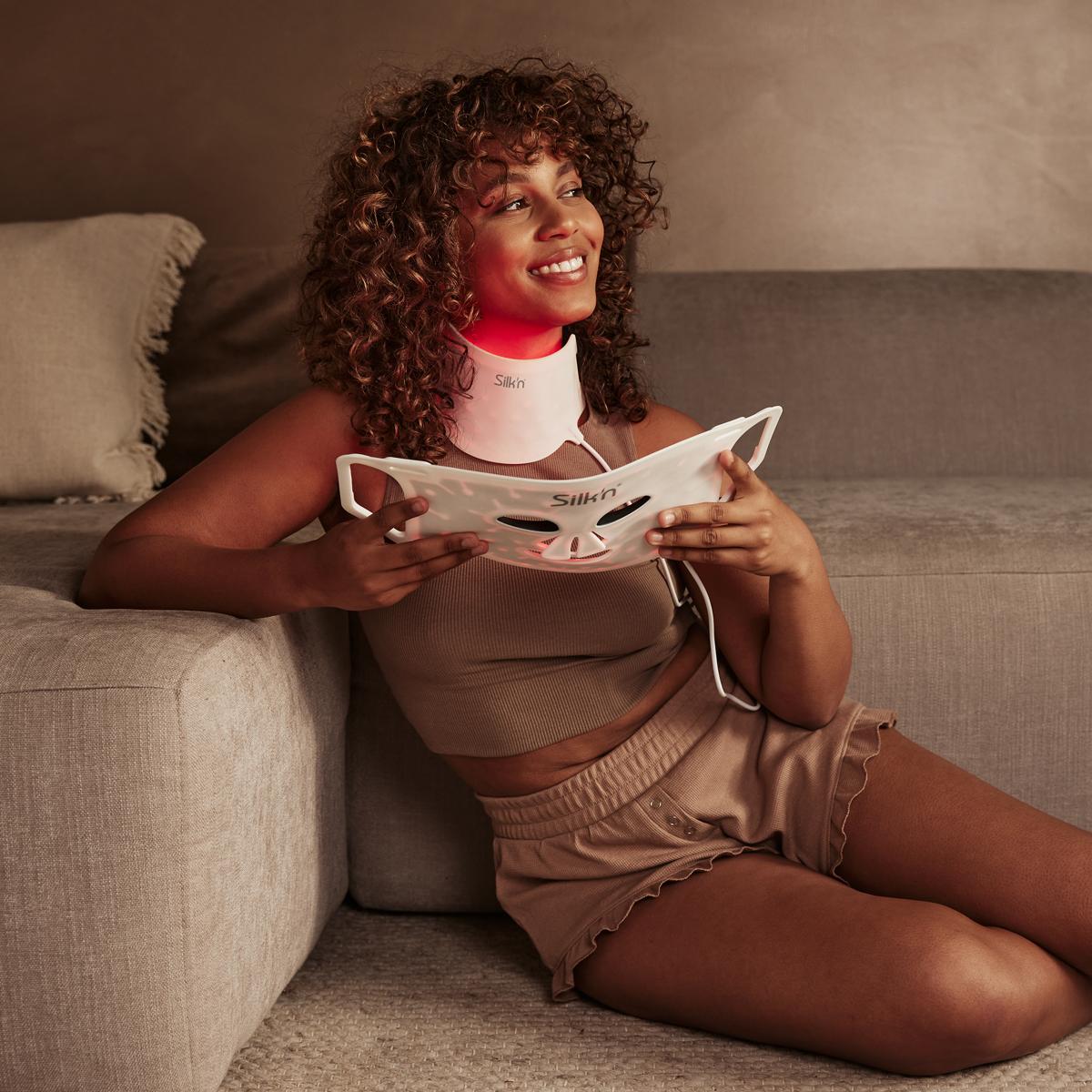 Woman using the Red Light Therapy Neck Mask together with LED Face Mask