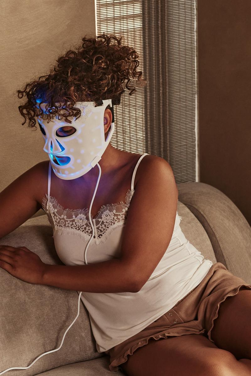 Benefits of LED Face Mask: woman using a LED face mask - blue light therapy