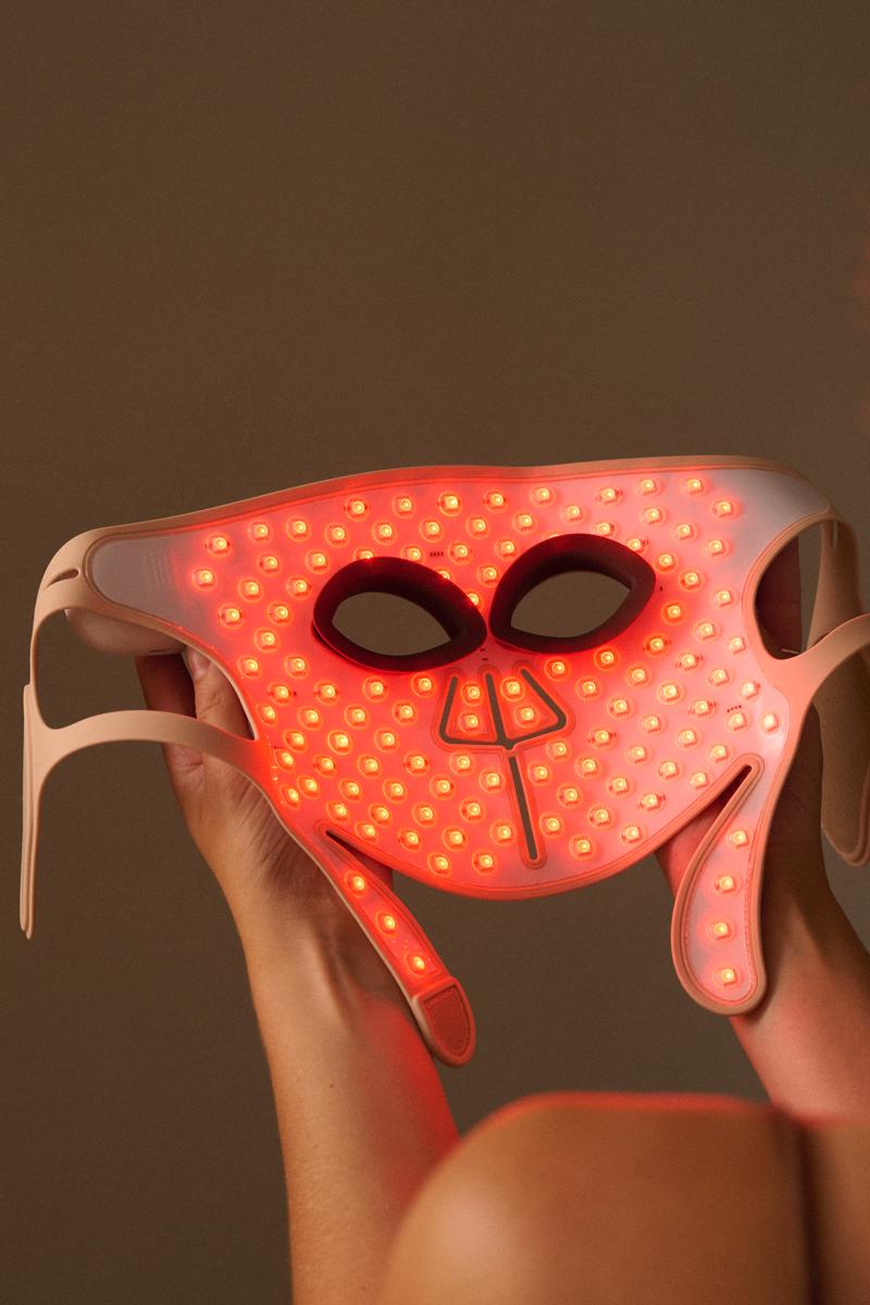 Woman holding the LED Face Mask Pro from Silk'n with red lights showing at the inside of the mask