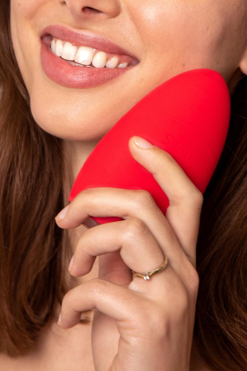 Femme souriante utilisant l&rsquo;appareil rouge Bright pour le nettoyage du visage