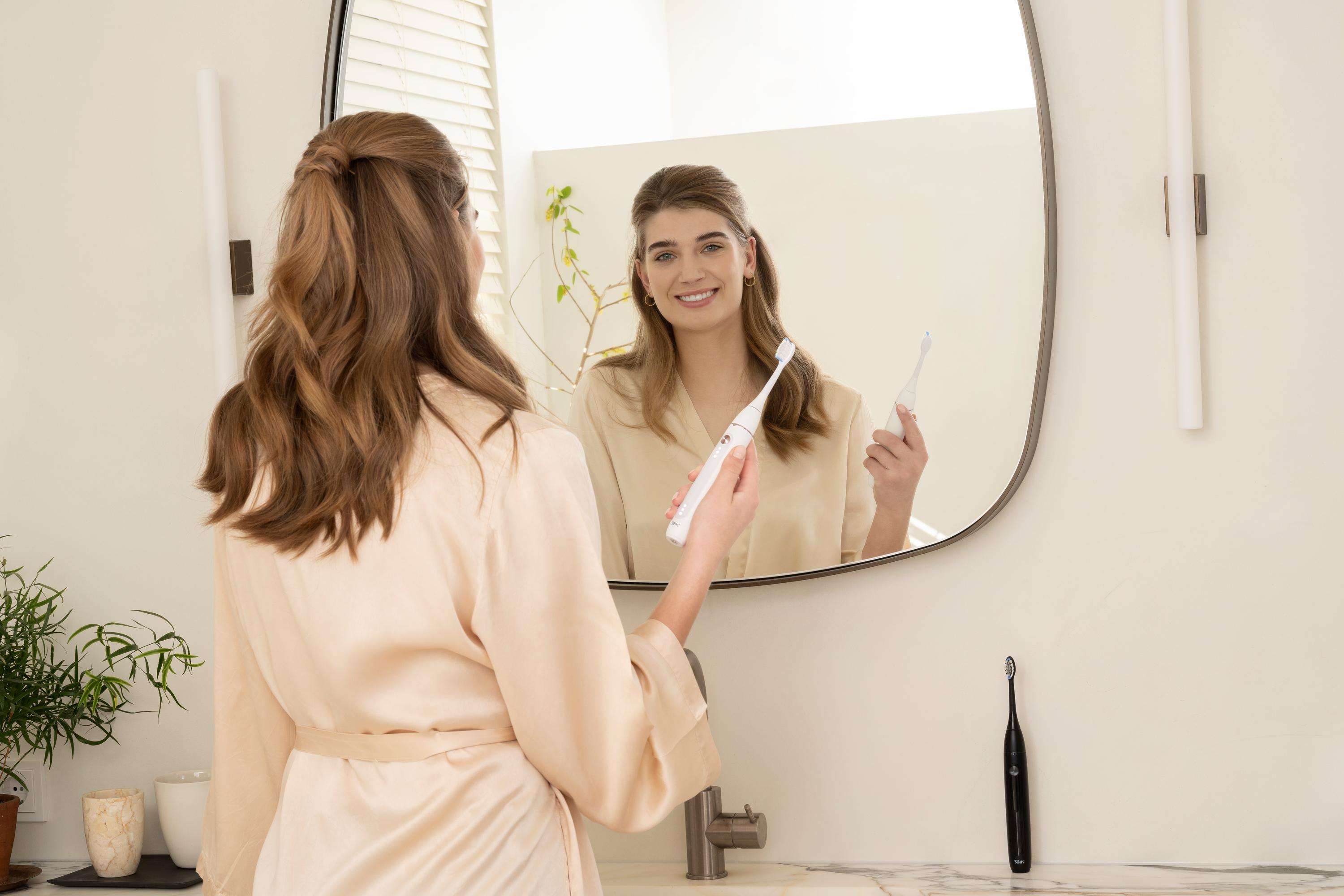 Woman with a bright smile using the sonic toothbrush SonicYou