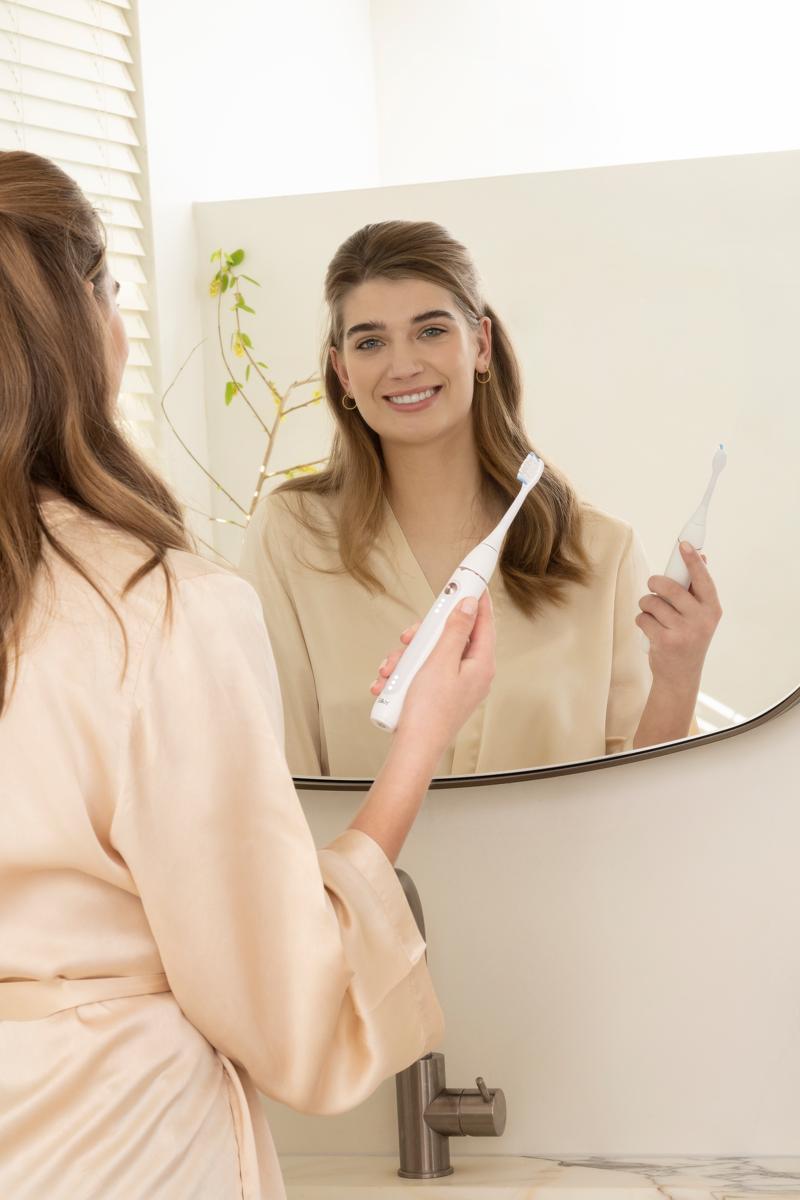 Woman with a bright smile using the sonic toothbrush SonicYou