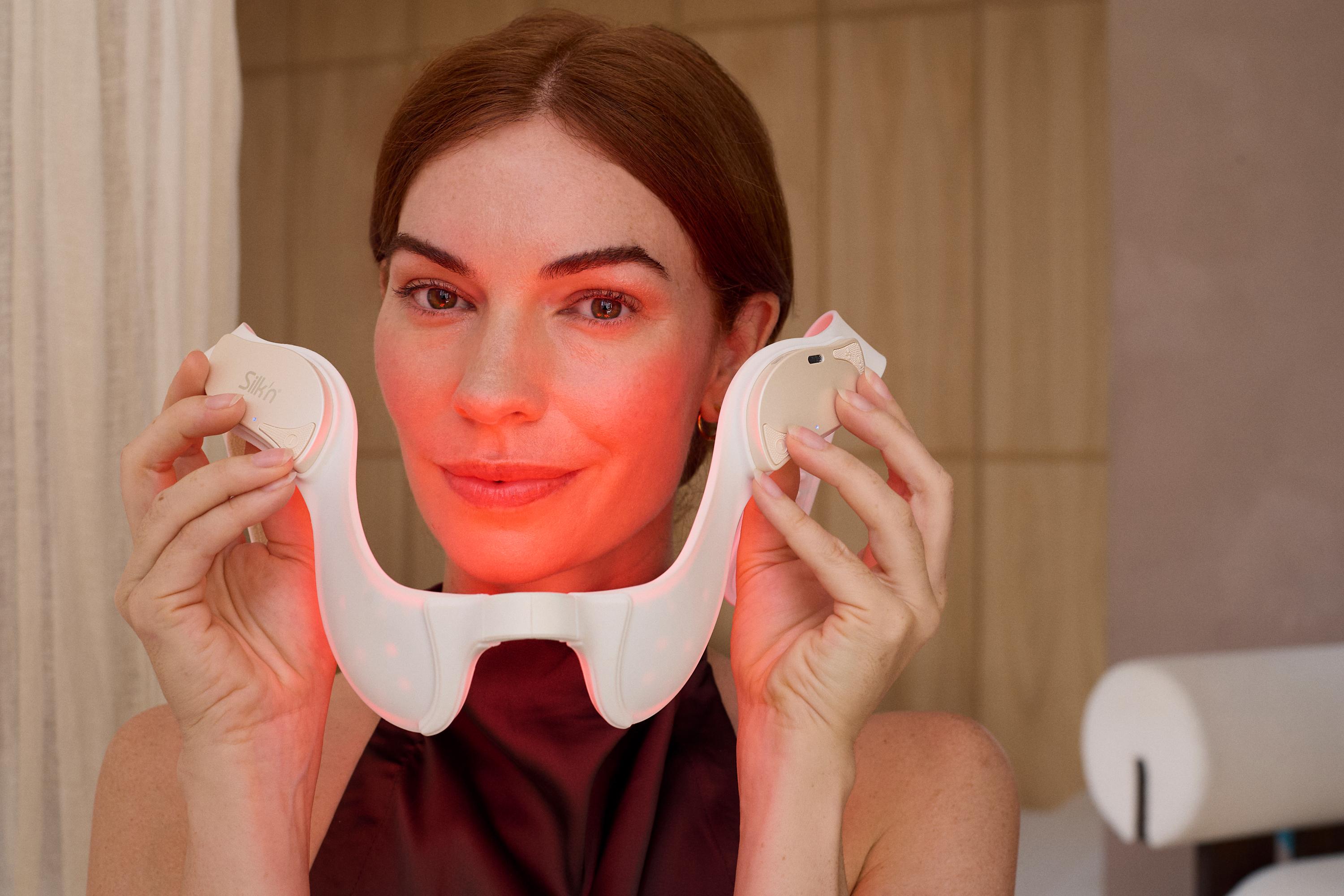 Woman putting on the red light device Silk'n LED TriLyft