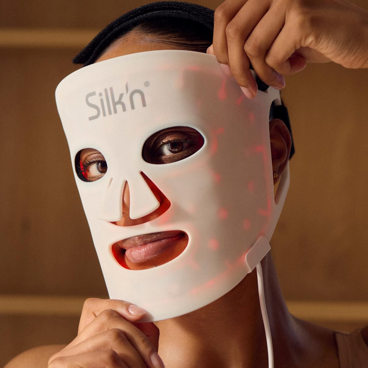 Woman with darker skin putting on the Silk'n LED Face Mask 100 with red light therapy