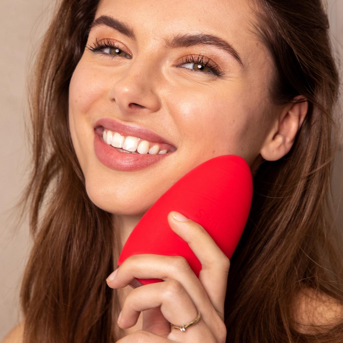 Femme souriante utilisant l&rsquo;appareil rouge Bright pour le nettoyage du visage