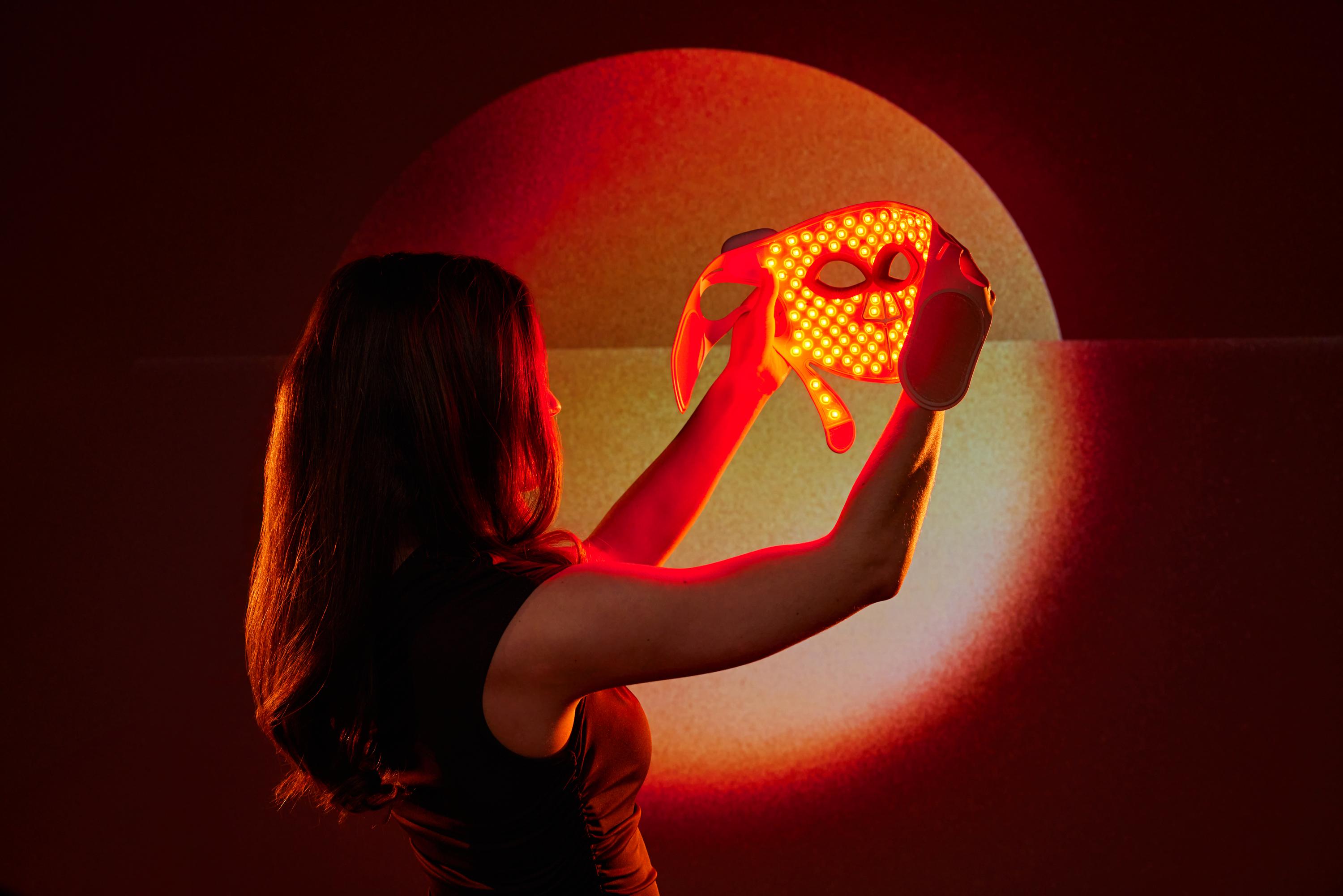 Woman watching her LED Face Mask Pro with red light