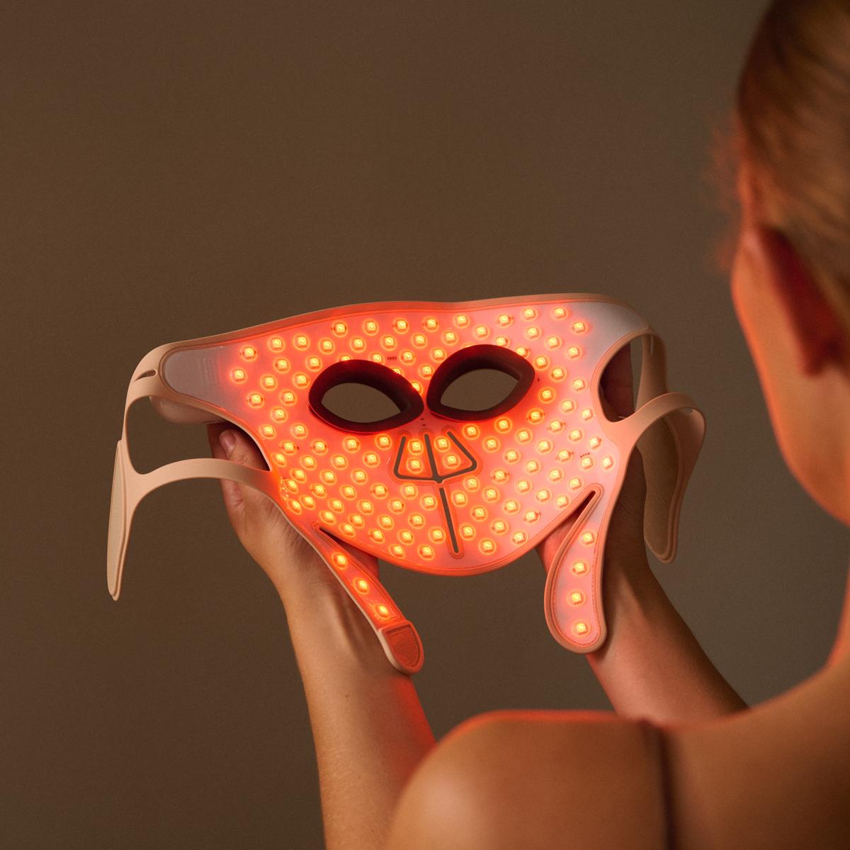 Woman holding the Silk'n LED Face Mask Pro with amber light