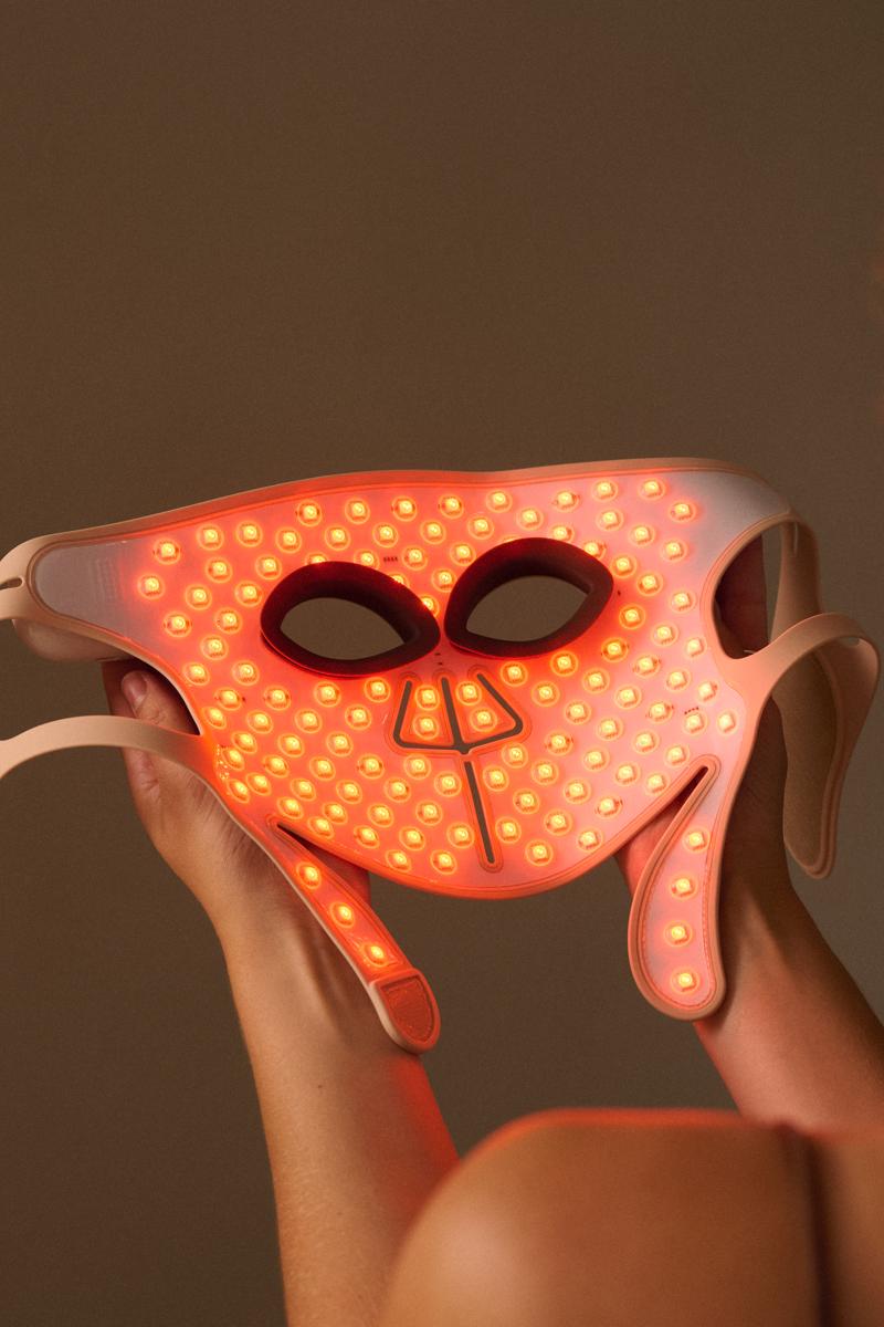 Woman holding the Silk'n LED Face Mask Pro with amber light
