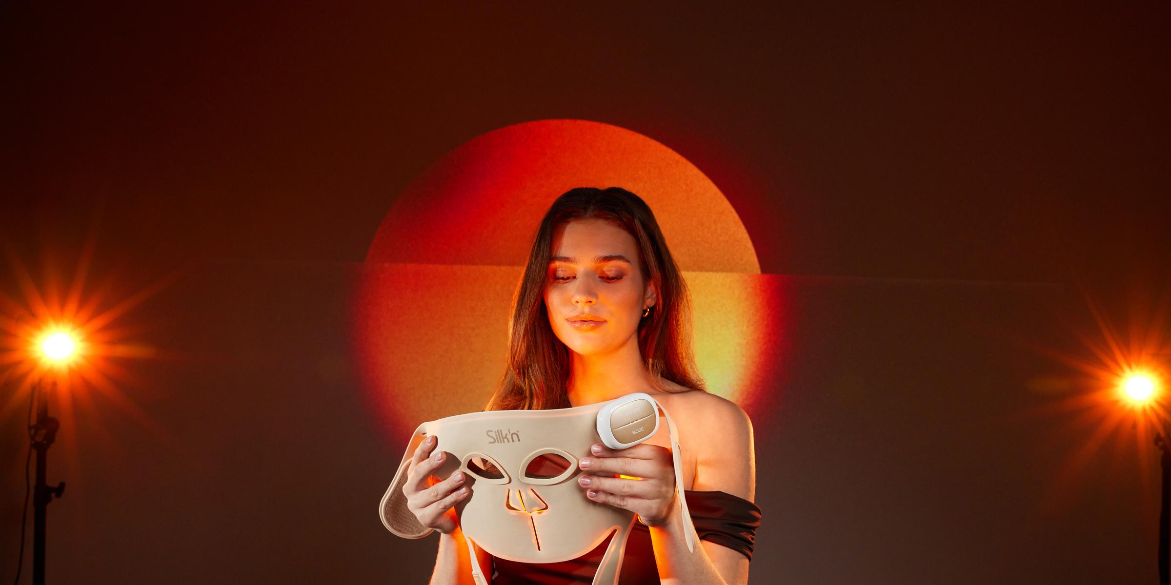 Radiant woman holding her LED face mask