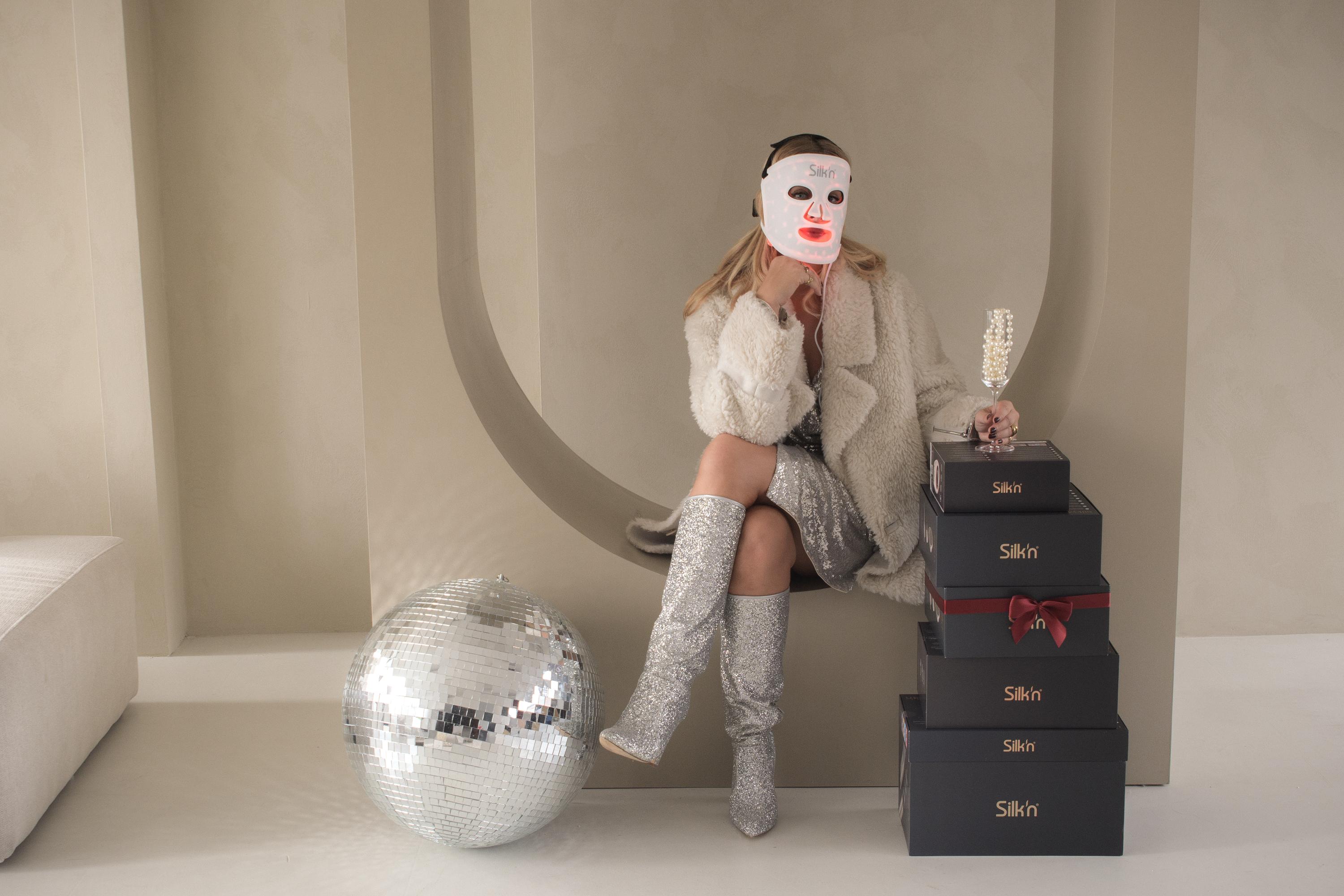 Woman wearing the Silk'n LED Face Mask 100 in festive season setting